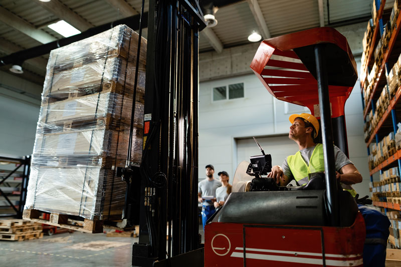 Operario trabajadno en empresa de cartón, con carretilla elevadora